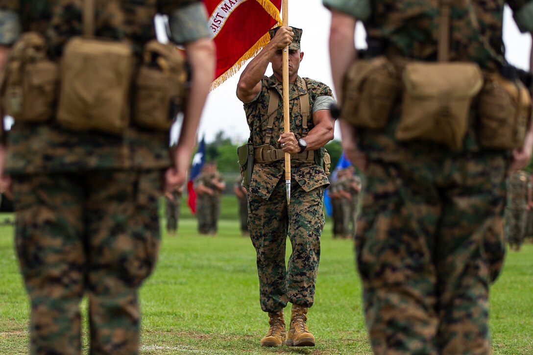 Sergeant Maj. Edwin Mota, sergeant major of the 31st Marine Expeditionary Unit, carries the unit guidon to Col. Tye R. Wallace during a change of command ceremony at Camp Hansen, Okinawa, Japan, June 13, 2018.