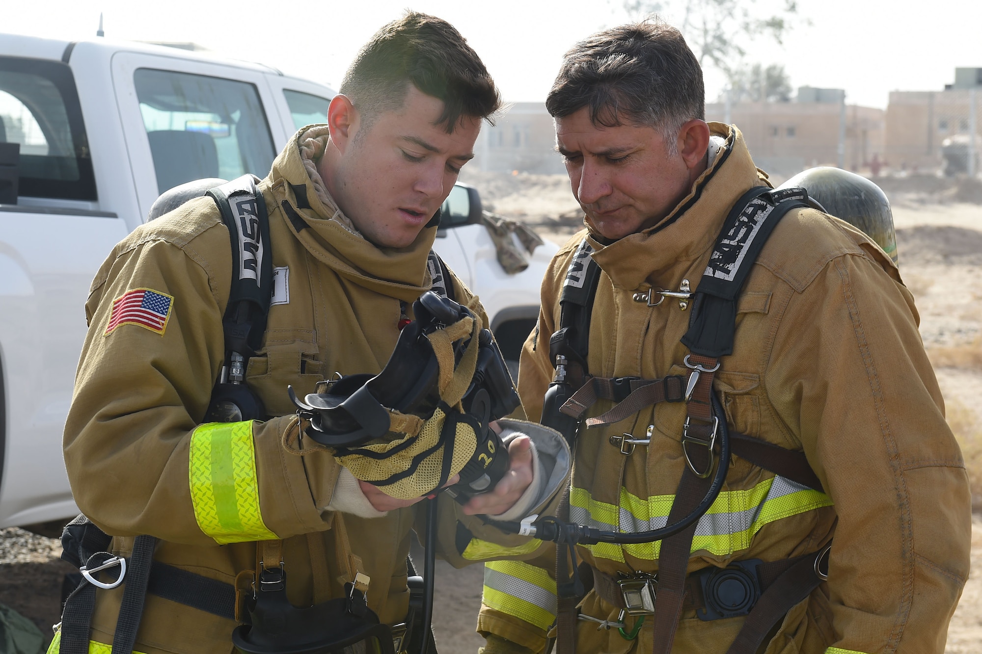 men in firefighter suits look at mask