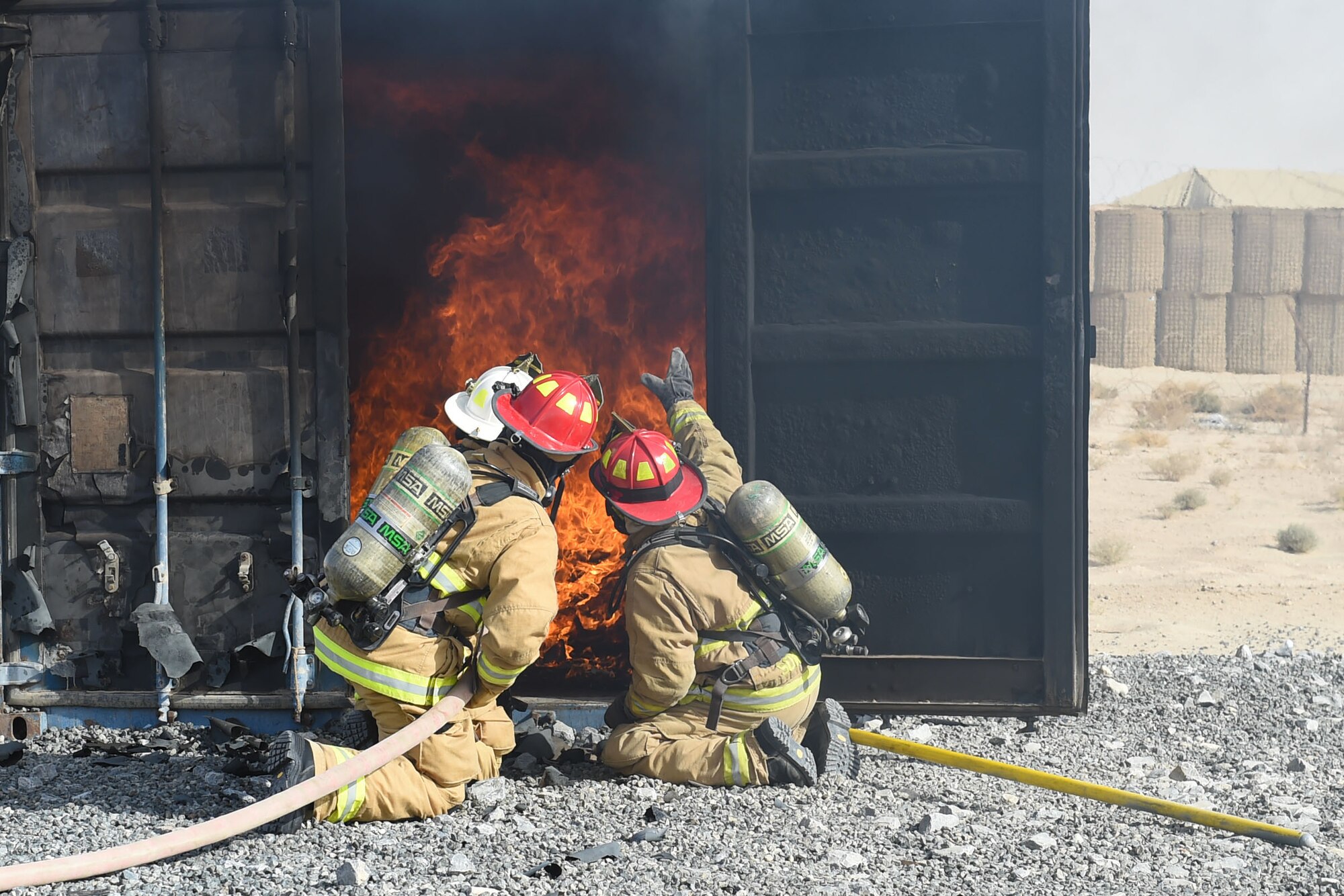 three firefighters spray water hose onto fire