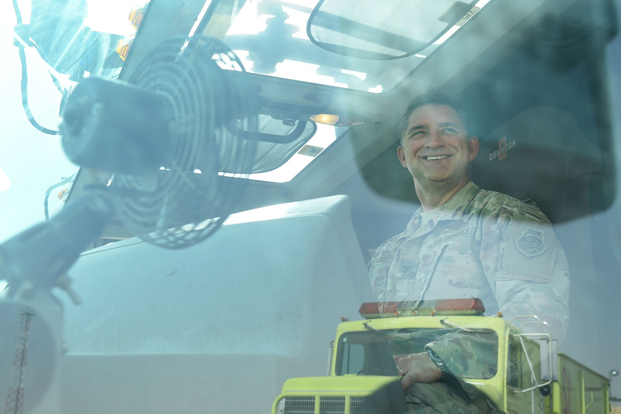 airman sits in fire truck smiling