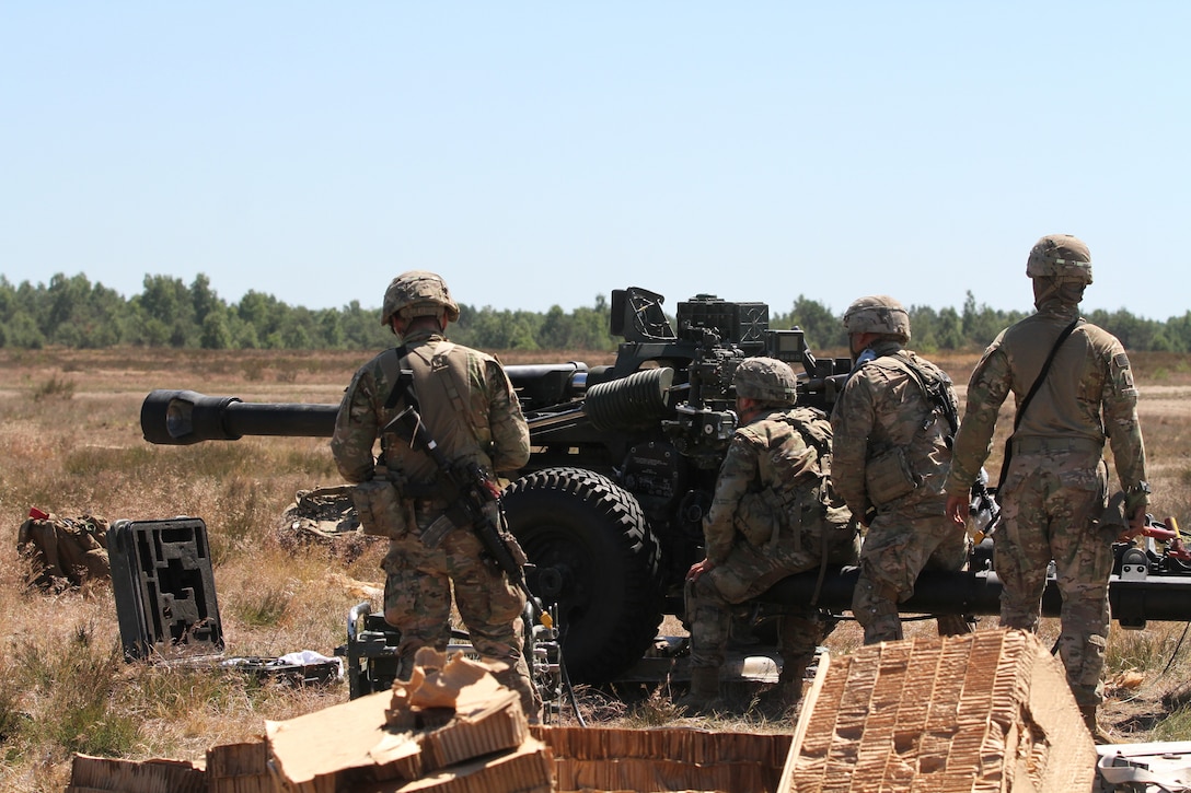 Soldiers prepare to fire an M119 105 mm howitzer.