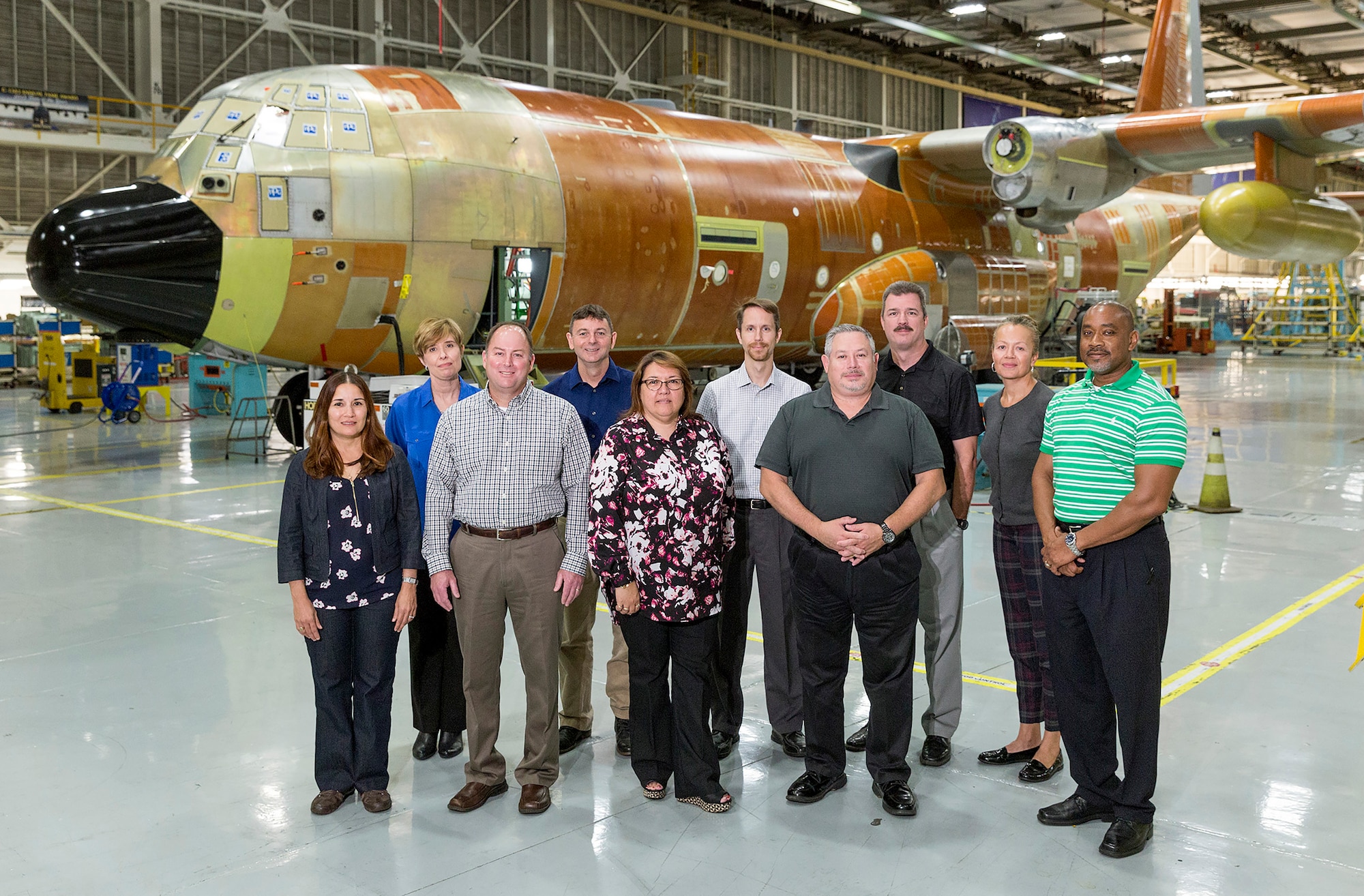 People posing for a photo behind an old airframe.