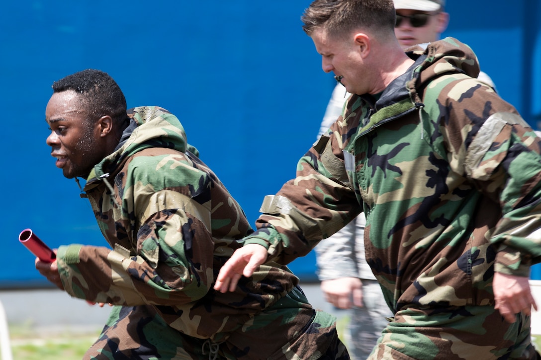 An Air Force officer passes the relay race baton to an enlisted airman during the Ability to Survive and Operate Rodeo.