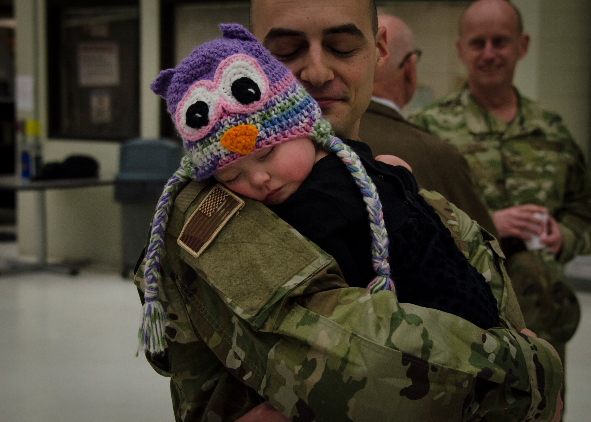 A deploying U.S. service member with the 128th Air Refueling Wing, Wisconsin Air National Guard, embraces his daughter after a sendoff ceremony at General Mitchell Air Field in Milwaukee, Wisconsin, Dec. 2, 2017.