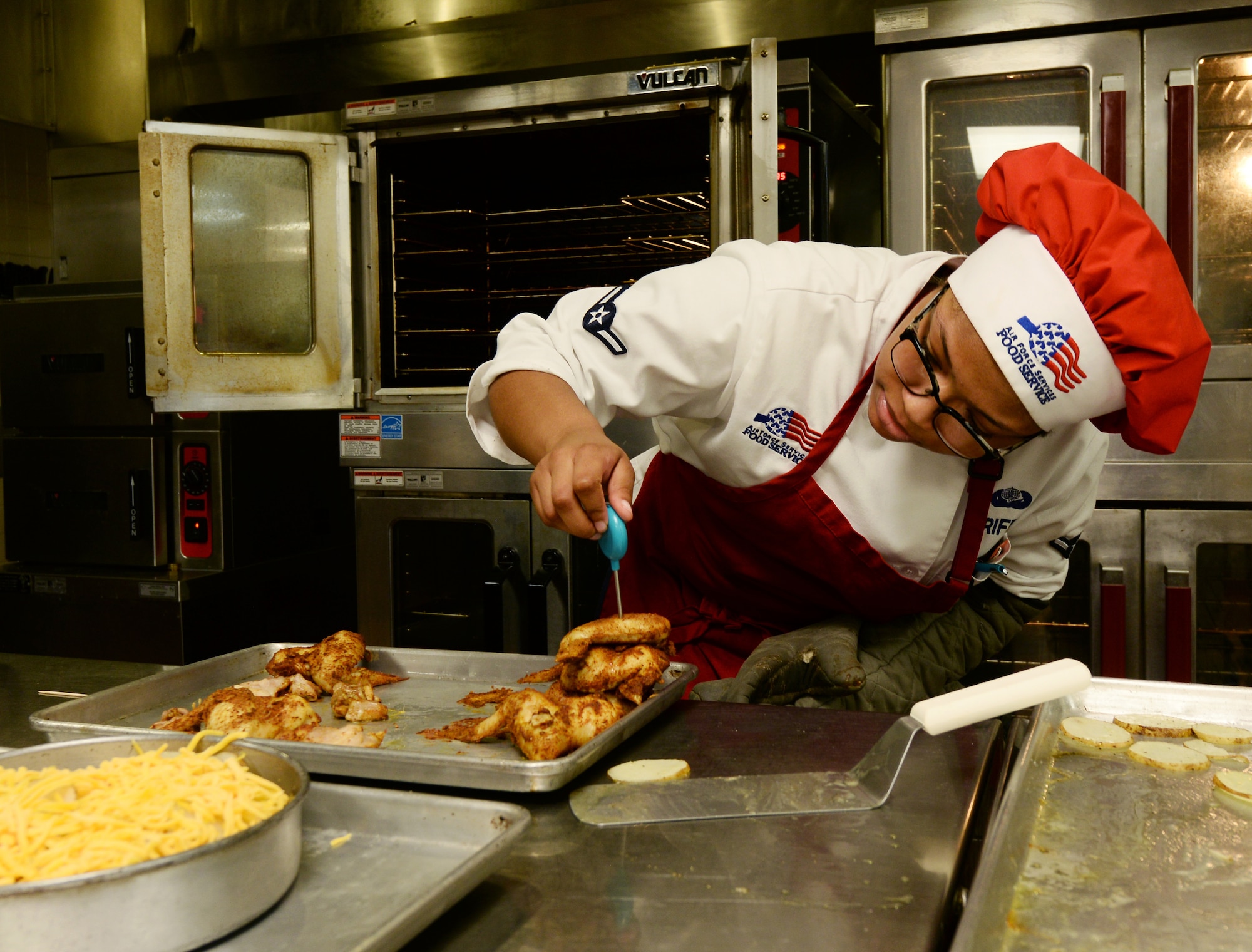 Airman Aminah Griffin, 55th Force Support Squadron Sustainment Flight food service apprentice, checks the temperature of her chicken during a top chef competition inside the King dining facility May 31, 2018 at Offutt Air Force Base, Nebraska. Each team had 20 minutes to create an appetizer and 30 minutes for each entrée and dessert. (U.S. Air Force photo by Charles J. Haymond)