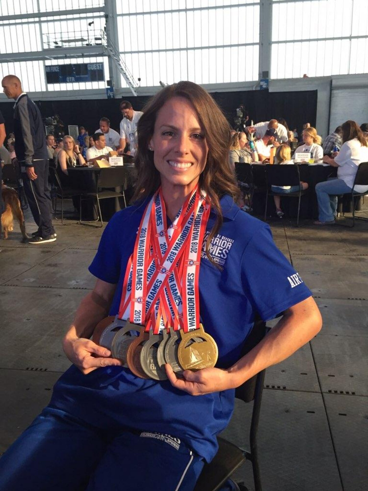 Smiling woman proudly displays gold, silver, and bronze medals around neck
