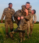 U.S. Air Force Airman 1st Class Nicholas Smoak, 633rd Security Forces Squadron entry controller, fireman carries another candidate during an emergency services team tryouts at Joint Base Langley-Eustis, Virginia, June 8, 2018. During the fitness obstacle course, the five first responders performed a low crawl, high crawl, ammunition can carry and a fireman carry. (U.S. Air Force photo by Senior Airman Derek Seifert)