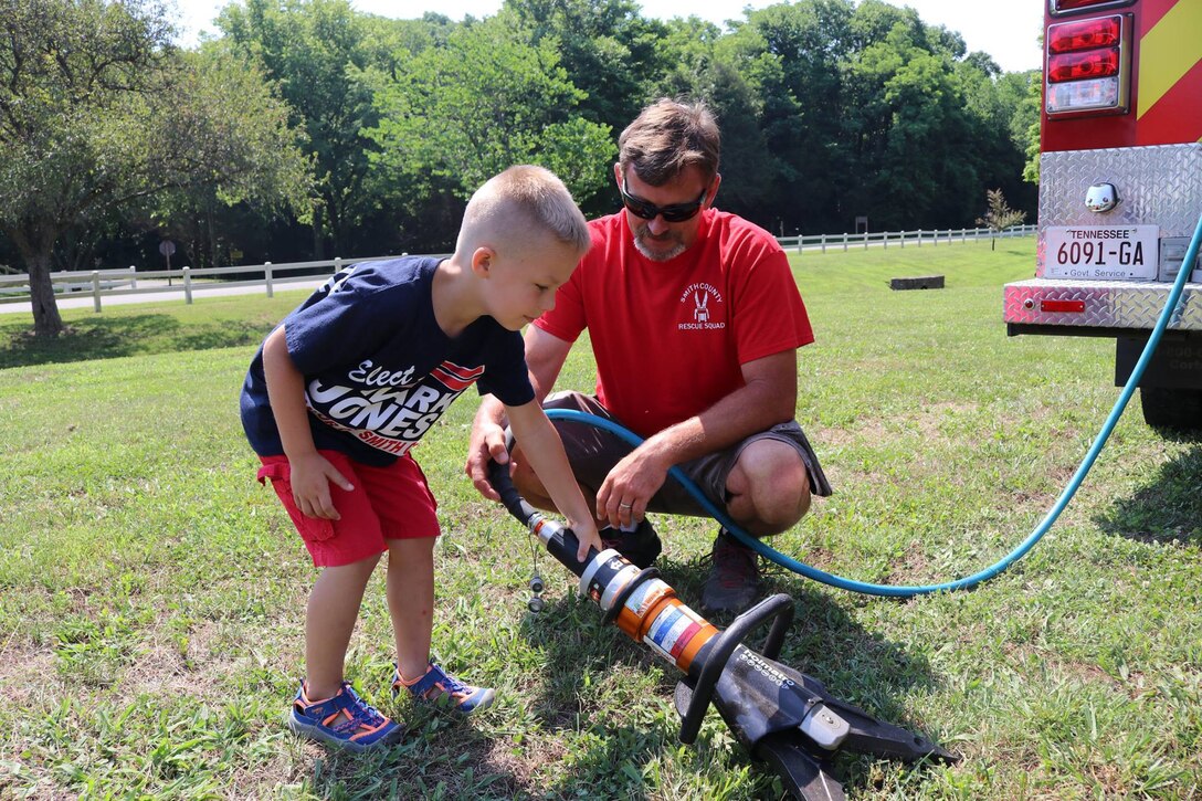 A member of the Smith County Rescue Squad Extrication team shows off the “jaws of life” to a youngster during the “Touch a Truck” event June 9, 2018 at Cordell Hull Lake in Carthage, Tenn. (USACE Photo by Ashley Webster)