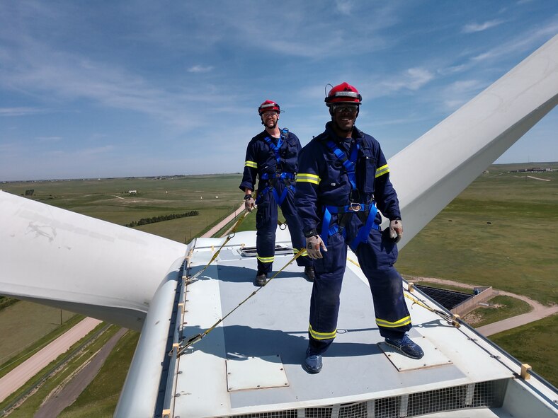 Jeremie Barrett, 90th Civil Engineer Squadron lead firefighter captain, and Senior Airman LeJarrell Evans, 90th Civil Engineering Squadron firefighter, stand on top of the wind turbine nacelle on F.E. Warren Air Force Base, Wyo., June 6, 2018. After completing the training portion of the 3M Capital Safety Wing Turbine Climb Safety and Tower Rescue certification, the firemen from 90th CES were able to climb the approximately 240 stair wind turbine. (Courtesy Photo)
