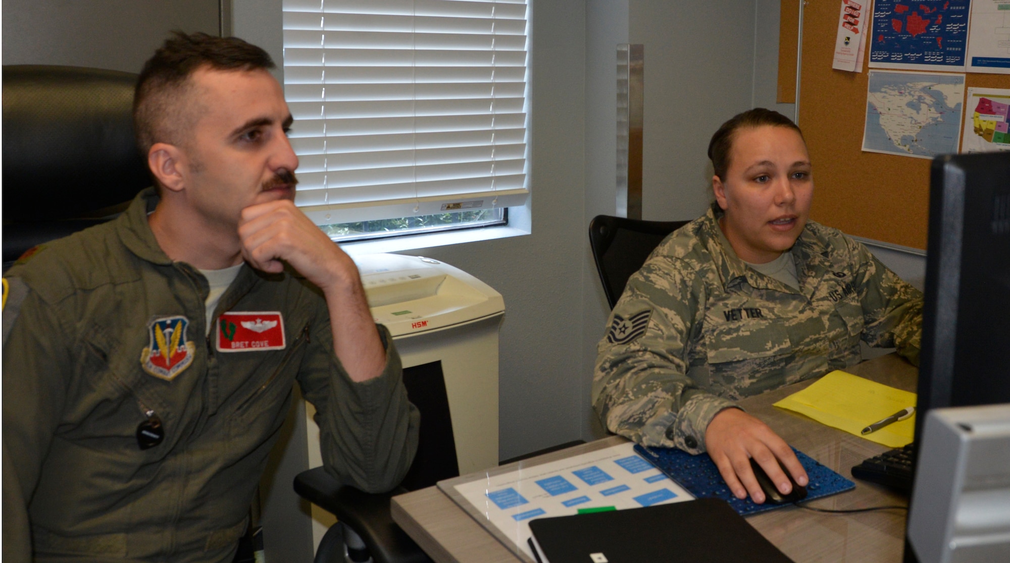 Maj. Bret Cove, Air Force Rescue Coordination Center Assistant Director of Operations, listens as Tech. Sgt. Brittany Vetter, AFRCC Operations Flight NCO in Charge, reviews the day’s notifications during a shift change in the AFRCC operations room. (Photo by Mary McHale)
