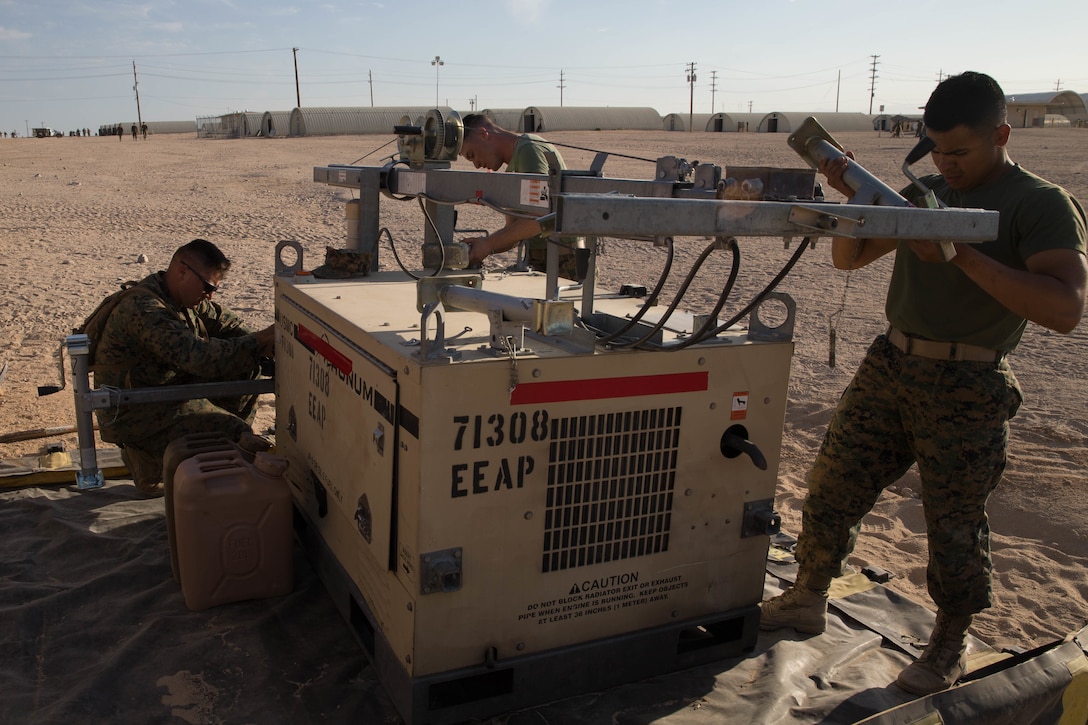 Staff Sgt. Lucas White, an engineer equipment electrical systems technician with Maintenance Company, Combat Logistics Battalion 451, Combat Logistics Regiment 45, 4th Marine Logistics Group, teaches Lance Cpl. Eli Sommers, a refrigeration and air conditioning technician with Utilities, CLR-45, 4th MLG, and Private First Class Sergio Gonzalez, a motor vehicle operator with CLB-451, CLR-45, 4th MLG, how to set up a floodlight during Integrated Training Exercise 4-18 at Marine Corps Air Ground Combat Center Twentynine Palms, California, June 12, 2018.