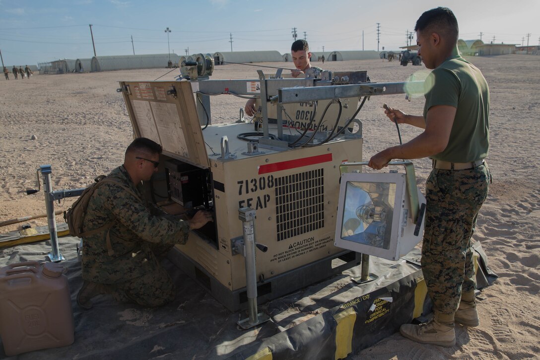 Staff Sgt. Lucas White, an engineer equipment electrical systems technician with Maintenance Company, Combat Logistics Battalion 451, Combat Logistics Regiment 45, 4th Marine Logistics Group, Lance Cpl. Eli Sommers, a refrigeration and air conditioning technician with Utilities, CLR-45, 4th MLG, and Private First Class Sergio Gonzalez, a motor vehicle operator with CLB-451, CLR-45, 4th MLG, set up a floodlight during Integrated Training Exercise 4-18 at Marine Corps Air Ground Combat Center Twentynine Palms, California, June 12, 2018