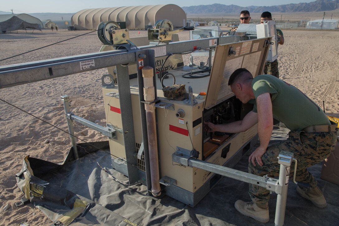 Staff Sgt. Lucas White, an engineer equipment electrical systems technician with Maintenance Company, Combat Logistics Battalion 451, Combat Logistics Regiment 45, 4th Marine Logistics Group, Lance Cpl. Eli Sommers, a refrigeration and air conditioning technician with Utilities, CLR-45, 4th MLG, and Private First Class Sergio Gonzalez, a motor vehicle operator with CLB-451, CLR-45, 4th MLG, set up a floodlight during Integrated Training Exercise 4-18 at Marine Corps Air Ground Combat Center Twentynine Palms, California, June 12, 2018.