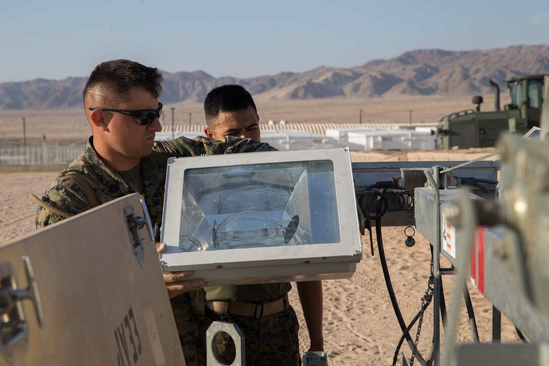 Staff Sgt. Lucas White, an engineer equipment electrical systems technician with Maintenance Company, Combat Logistics Battalion 451, Combat Logistics Regiment 45, 4th Marine Logistics Group, and Private First Class Sergio Gonzalez, a motor vehicle operator with CLB-451, CLR-45, 4th MLG, attach a floodlight to its base during Integrated Training Exercise 4-18 at Marine Corps Air Ground Combat Center Twentynine Palms, California, June 12, 2018.