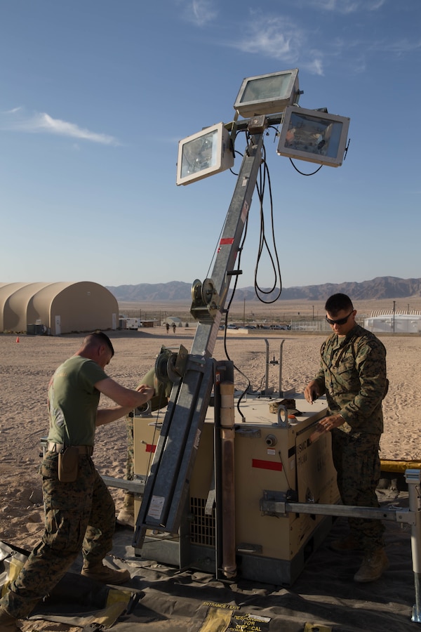 Staff Sgt. Lucas White, an engineer equipment electrical systems technician with Maintenance Company, Combat Logistics Battalion 451, Combat Logistics Regiment 45, 4th Marine Logistics Group, and Lance Cpl. Eli Sommers, a refrigeration and air conditioning technician with Utilities, CLR-45, 4th MLG, raise a floodlight during Integrated Training Exercise 4-18 at Marine Corps Air Ground Combat Center Twentynine Palms, California, June 12, 2018. Marines with the Exercise Support Element of ITX 4-18 provided food service, arrival and departure processing, bulk fuel, camp engineering and camp sustainment services to over 5,500 Marines throughout the course of the exercise. (U.S. Marine Corps photo by Lance Cpl. Samantha Schwoch/released)