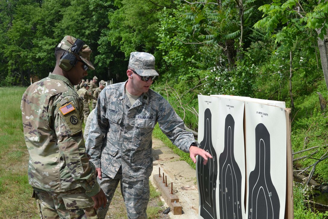 Air Force Cadet Patrick Forbus pinpoints the area on the pistol target that he successfully shot during the German Armed Forces Proficiency Badge pistol markmanship test. Forbus was one of more than 75 Soldiers and Airmen who strived to earn the badge for military proficiency. (U.S. Army Reserve photo by Sgt. 1st Class Emily Anderson, 80th Training Command)