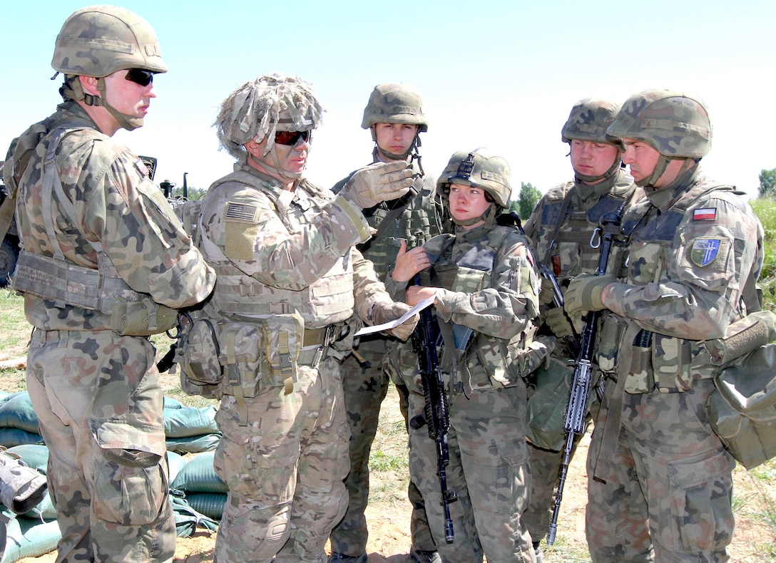 Army Staff Sgt. Marion Szwcyk, weapons squad leader from Apache Troop, 1st Squadron, 2nd Cavalry Regiment, Battle Group Poland, briefs Polish soldiers from the 15th Mechanized Brigade on range cards during Exercise Saber Strike 18 in Wyreby, Poland.