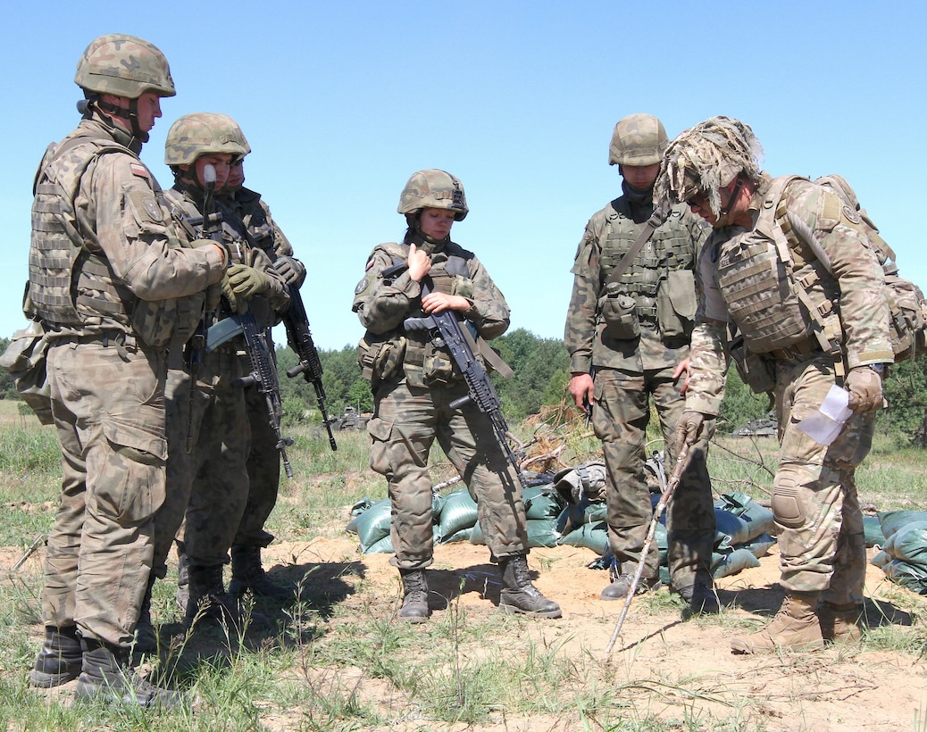 Army Staff Sgt. Marion Szwcyk, weapons squad leader from Apache Troop, 1st Squadron, 2nd Cavalry Regiment, Battle Group Poland, instructs Polish soldiers from the 15th Mechanized Brigade on space needed to dig fighting positions during Exercise Saber Strike 18 in Wyreby, Poland.
