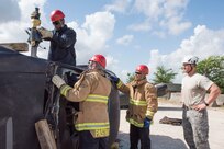 902nd Civil Engineer Squadron firefighters observe a simulated vehicle extrication rescue June 8, 2018 at Camp Talon, Joint Base San Antonio-Randolph. In this scenario, firefighters use a smaller form of the Jaws of Life to push the dashboard off the victim. (U.S. Air Force photo by: Airman Shelby Pruitt.)