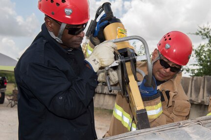 Jesus Rico and Esteban Perez, 902nd Civil Engineer Squadron firefighters, train using the Jaws of Life June 8, 2018 at Camp Talon, Joint Base San Antonio-Randolph. These men use the Jaws of Life to pry the lodged door open and simulate a vehicle extrication rescue. (U.S. Air Force photo by: Airman Shelby Pruitt.)