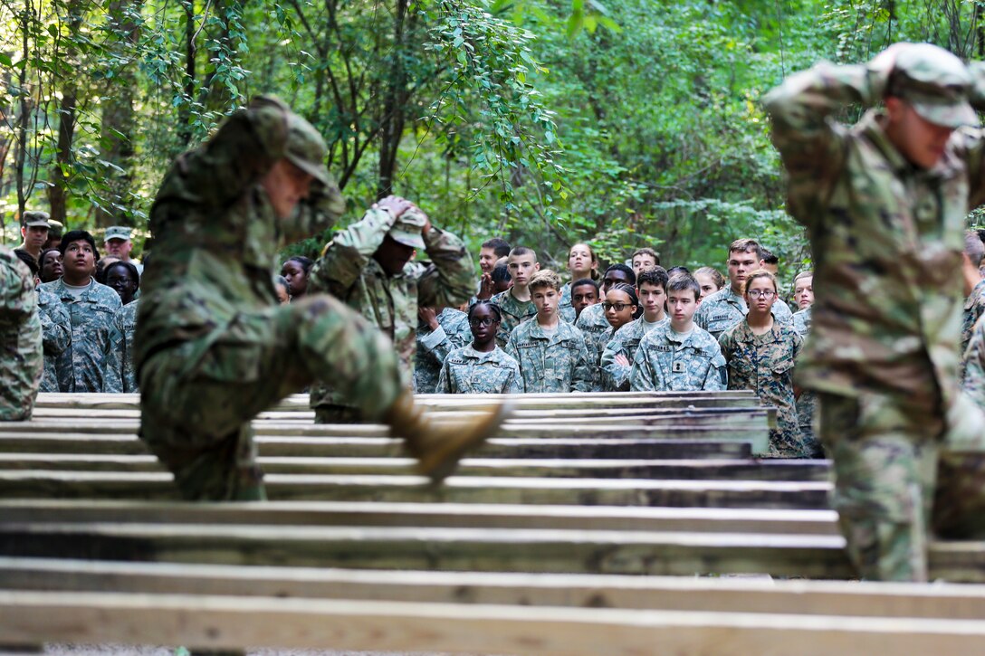 Army drill instructors demonstrate the correct method of going through an obstacle course.