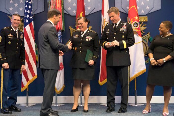 Army Secretary Mark Esper shakes hands and presents an award.