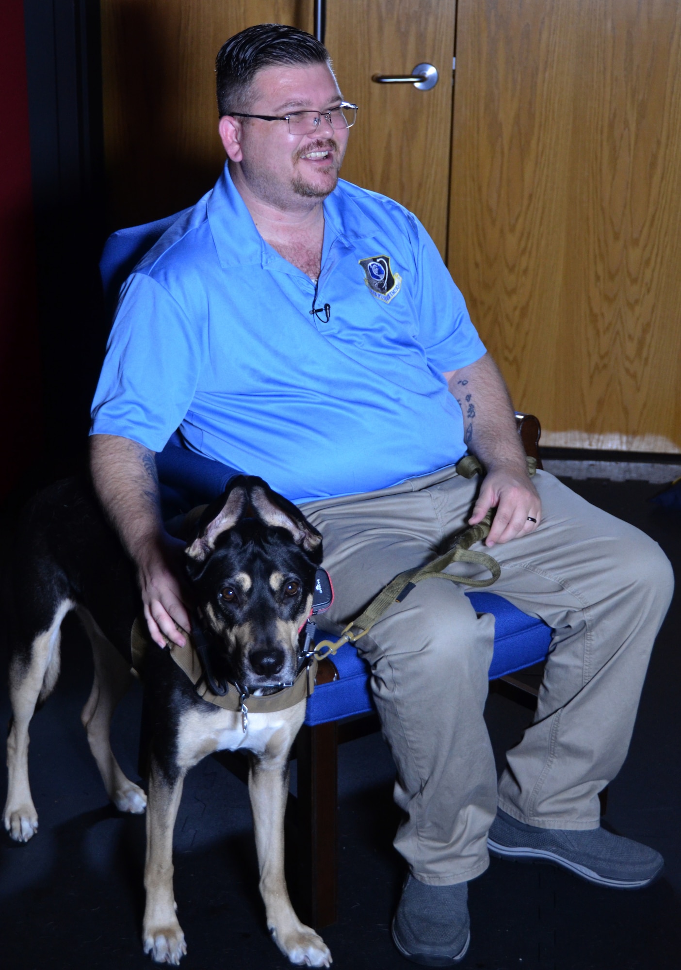 Ryan Kaono, a support agreement manager with the Air Force Installation and Mission Support Center, shares a laugh with a videographer during an interview while his service dog Romeo keeps a steady eye on the photographer. Romeo helps Kaono quickly recover from bouts of anxiety and night terrors related to enemy attacks while he was deployed to Saudi Arabia and Iraq. (U.S. Air Force photo by Armando Perez)