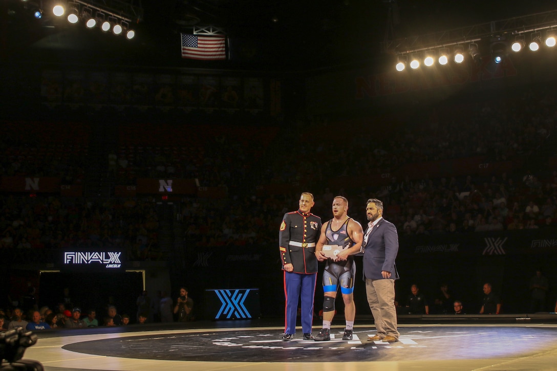 Staff Sgt. Craig Soltys, the staff noncommissioned officer-in-charge of Recruiting Substation Lincoln, presents a plaque to Kyle Snyder, Columbus, Ohio native, Olympic Gold Medalist, and world team member, at the FinalX Senior Freestyle World Team Trials at Bob Devaney Sports Center in Lincoln, Neb. June 9, 2018.