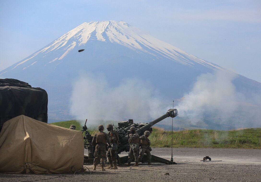 U.S. Marines with Bravo Battery, 3rd Battalion, 12th Marine Regiment, 3rd Marine Division, fire a round out of a M777A2 Howitzer