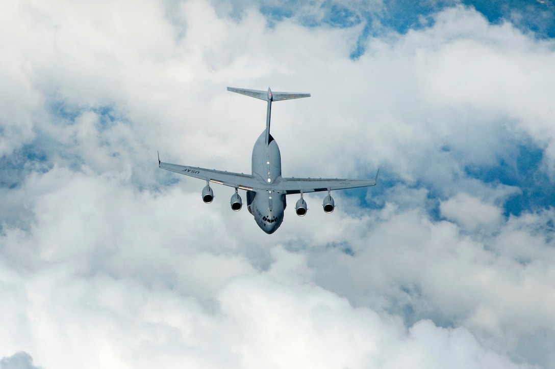 A C-17 Globemaster III flies toward a KC-135 Stratotanker refueling aircraft.