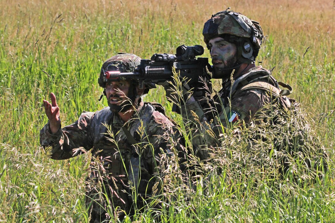 Italian soldiers discuss coordinate their follow-on attack during training.