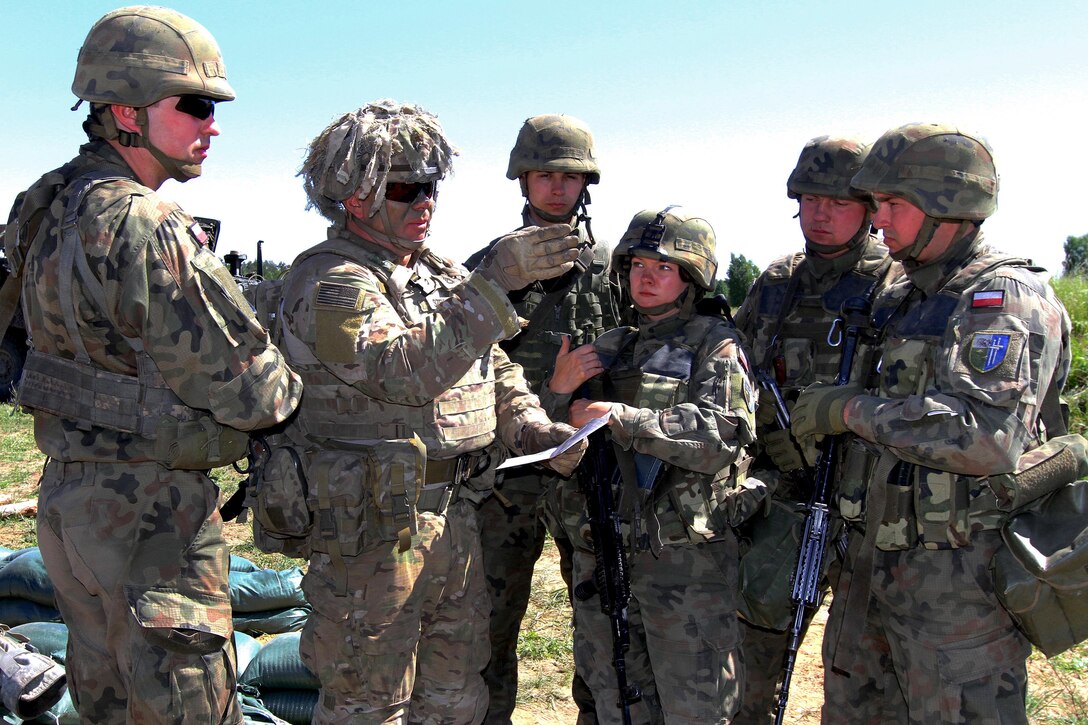 A U.S. soldier gives a safety brief and proper range card submission to Polish army soldiers.