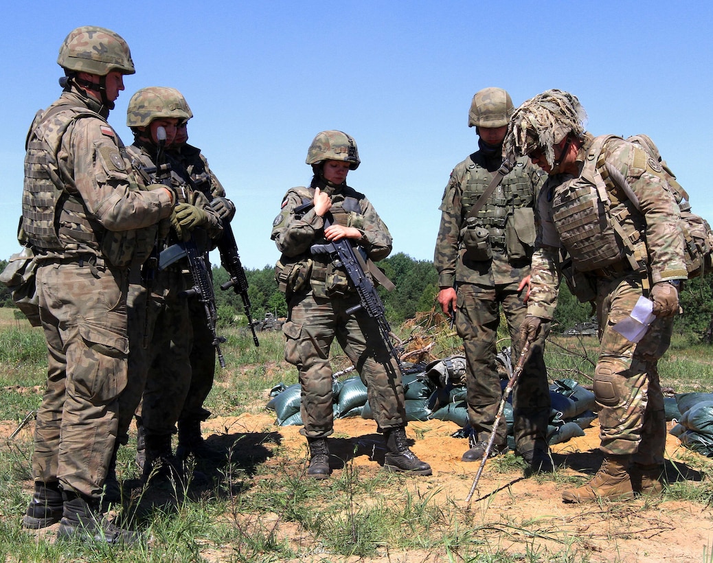 A U.S. soldier instructs Polish army soldiers on proper distance needed between multiple fighting positions.