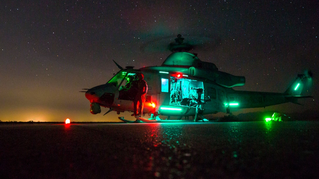 A helicopter sits on the ground at night.