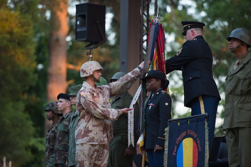 U.S. Army Soldiers from the 7th Transportation Brigade (Expeditionary) place battle streamers on the Army flag during the U.S. Army Training and Doctrine Command Band’s Music Under the Stars concert in honor of the Army’s 243rd Birthday at Joint Base Langley-Eustis, Va., June 15, 2018.