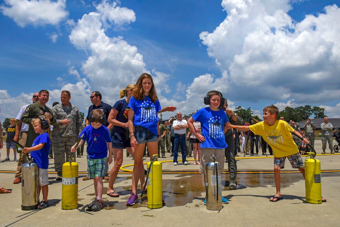 Five children and groups of airmen stand together.