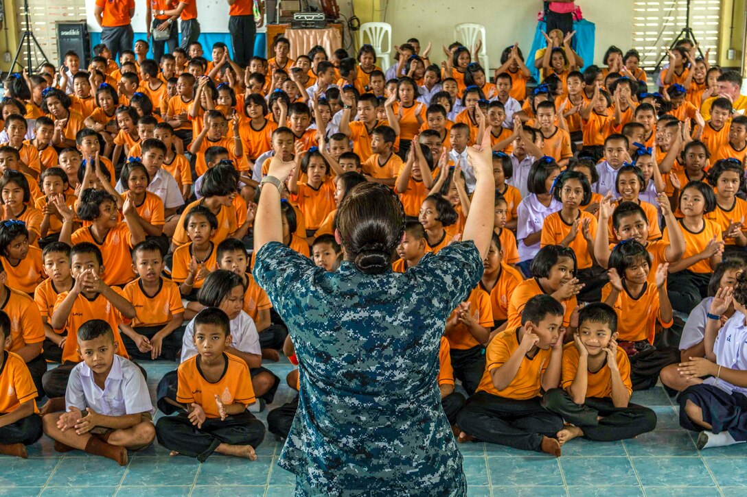A sailor stands in front of a group of children.