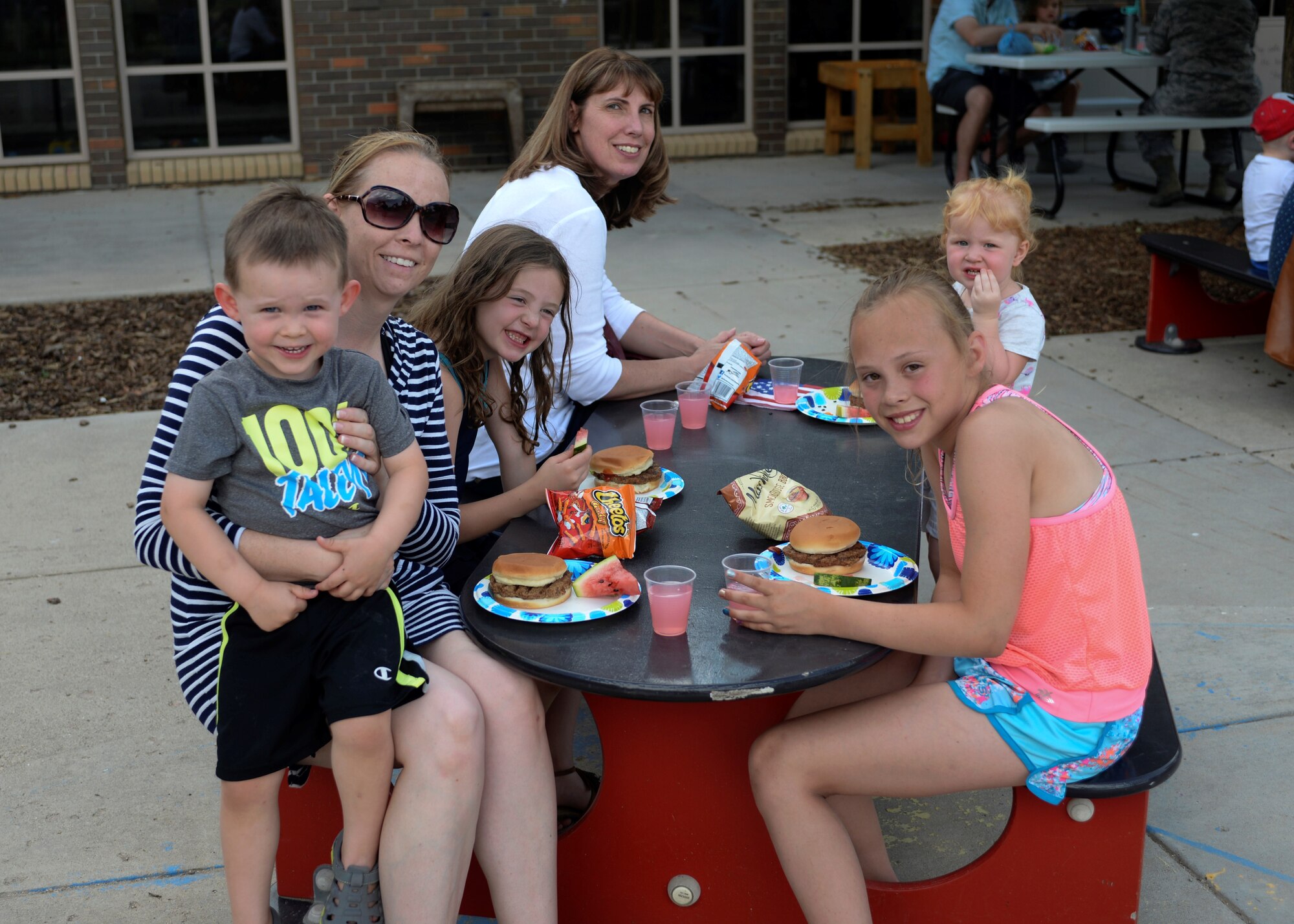 Families socialize over burgers and chips at the Child Development Center’s Eighth Annual Flag Day Picnic.  Ellsworth Child Development Center celebrated the national observance during their Eighth Annual Flag Day Picnic. (U.S. Air Force photo by Senior Airman Michella Stowers)