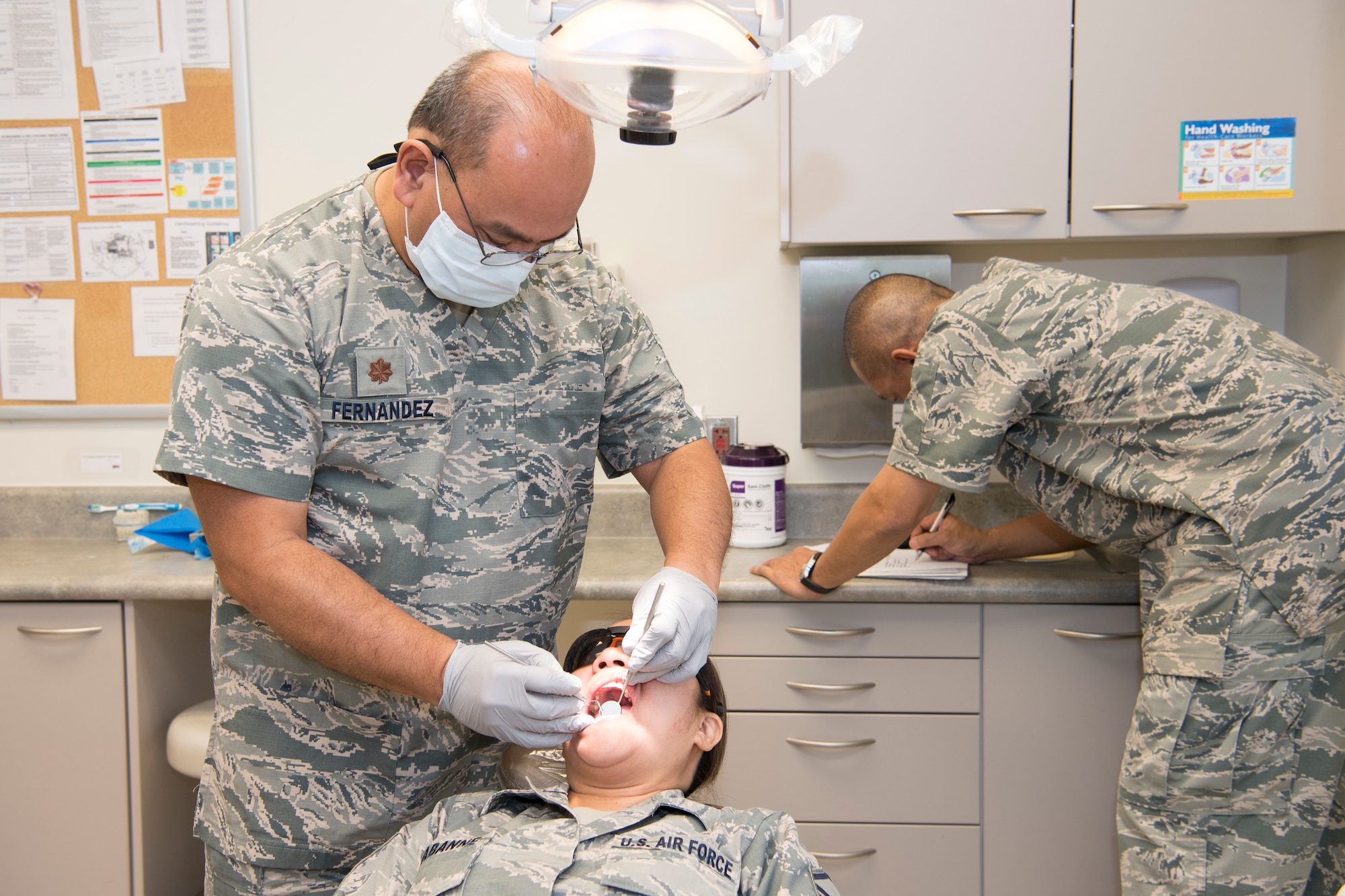 U.S. Air Force Maj. Michael Fernandez, Air Force Reserve’s 624th Aerospace Medicine Flight chief dentist, conducts a dental exam for Master Sgt. Jean Chabanne, Air National Guard’s 254th Air Base Group personalist, while Tech. Sgt. Vincent Nelson, 624th AMDF dental services non-commissioned officer in charge, scribes dental notes as part of individual medical readiness requirements during a unit training assembly at Andersen Air Force Base, Guam, June 3, 2018.
