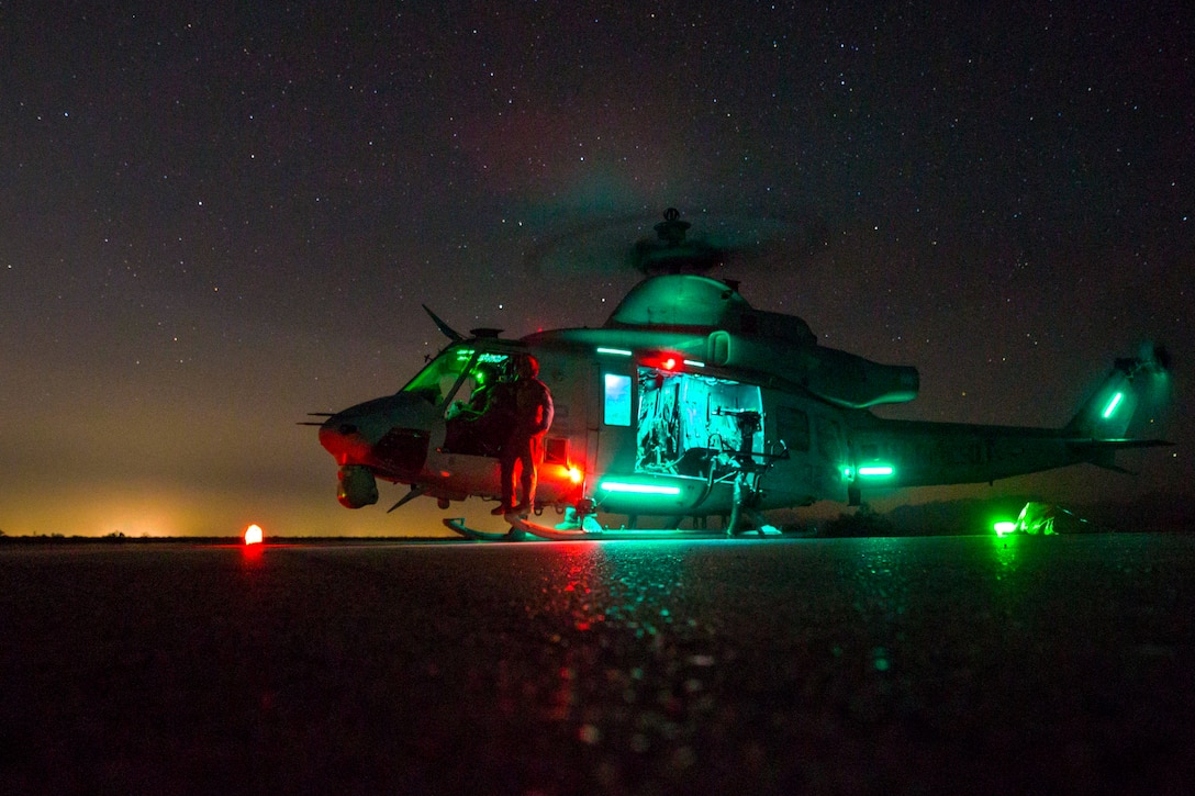 A helicopter sits on the ground at night.