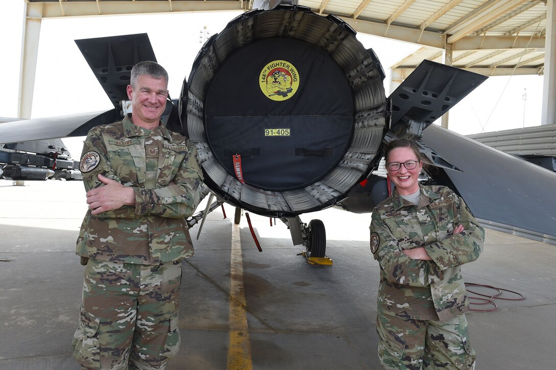 father and daughter stand behind F-16 Fighting Falcon