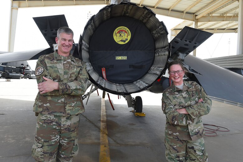 father and daughter stand behind F-16 Fighting Falcon