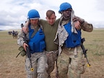 Alaska Army National Guard Spc. Dana Haddox and Spc. Jahmoi Hodge, both members of the platoon representing the 297th Regional Support Group, evacuate simulated casualty U.S. Navy Hospital Corpsman 3rd Class John Bustamonte, III Marine Expeditionary Force, June 17, 2018, during Tactical Combat Casualty Care training at Five Hills Training Area, Mongolia, as part of Khaan Quest 2018.