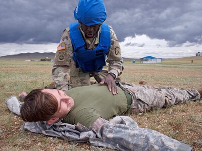 Alaska Army National Guard Spc. Jahmoi Hodge, a member of the platoon representing the 297th Regional Support Group, assesses simulated casualty U.S. Navy Hospital Corpsman 3rd Class John Bustamonte, III Marine Expeditionary Force, June 17, 2018, during Tactical Combat Casualty Care training at Five Hills Training Area, Mongolia, as part of Khaan Quest 2018.