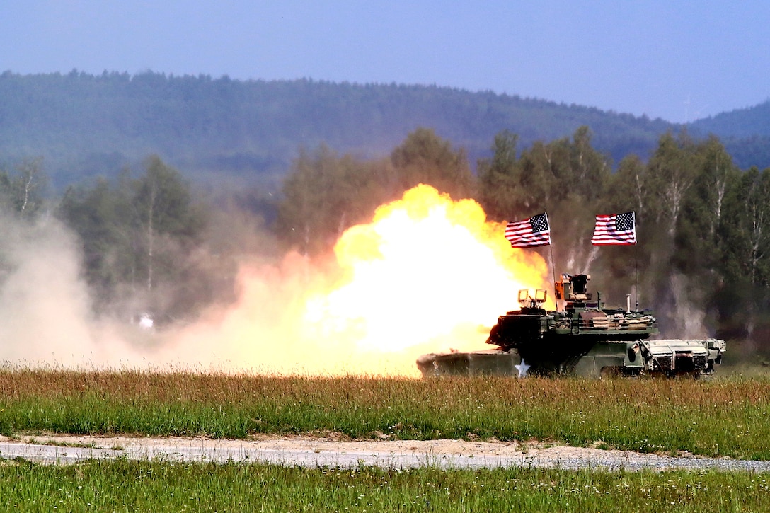 U.S. soldiers fire their M1A1 Abrams tank main battle gun at a target.