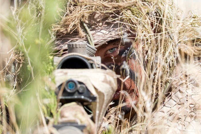 A sniper lays in the grass