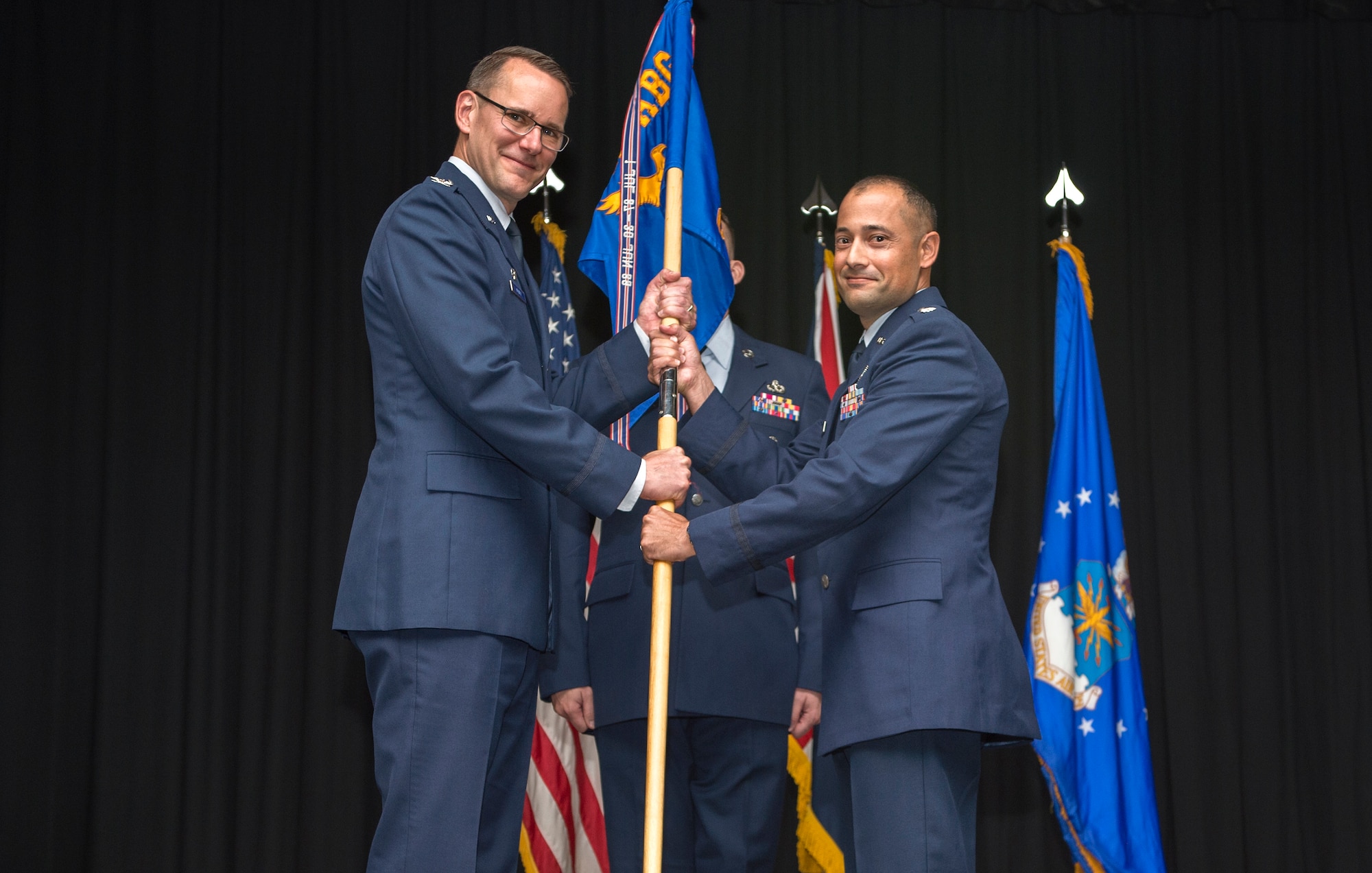 U.S. Air Force Col. Eric Oliver, 422th Air Base Group Commander, hands the guide-on to Lt. Col. Olexis Perez, 422nd Communications Squadron Commander, at RAF Fairford, June 14, 2018. The Change of Command Ceremony is done in front of the squadron to show the formal transfer of authority. (U.S. Air Force photo by Senior Airman Chase Sousa)