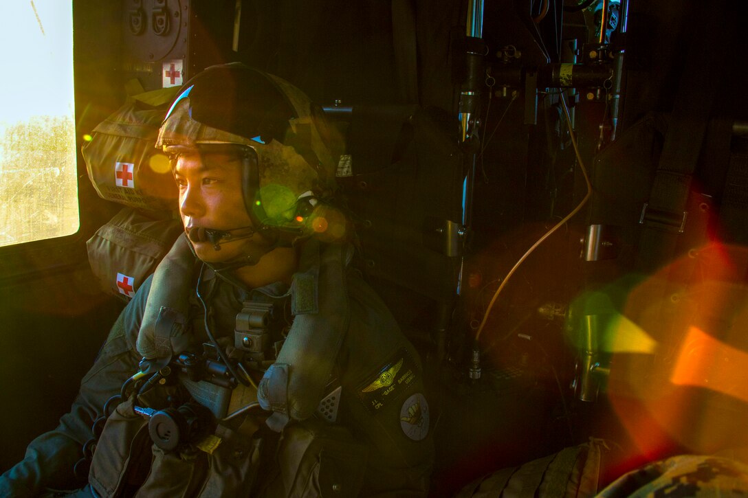A Marine sits in an aircraft with sun coming through the window.