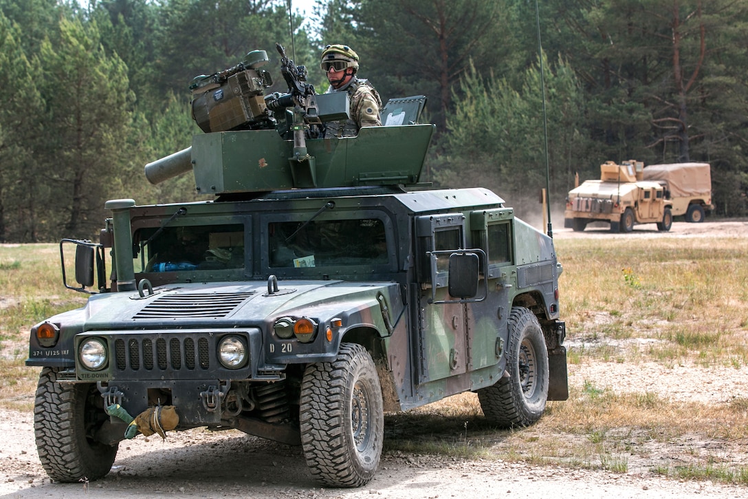 A soldier provides security from the gunner’s turret atop a Humvee.