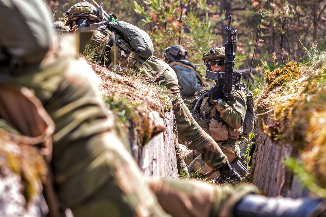 Norwegian soldiers provide suppressive fire, while a squad leader shouts out orders.